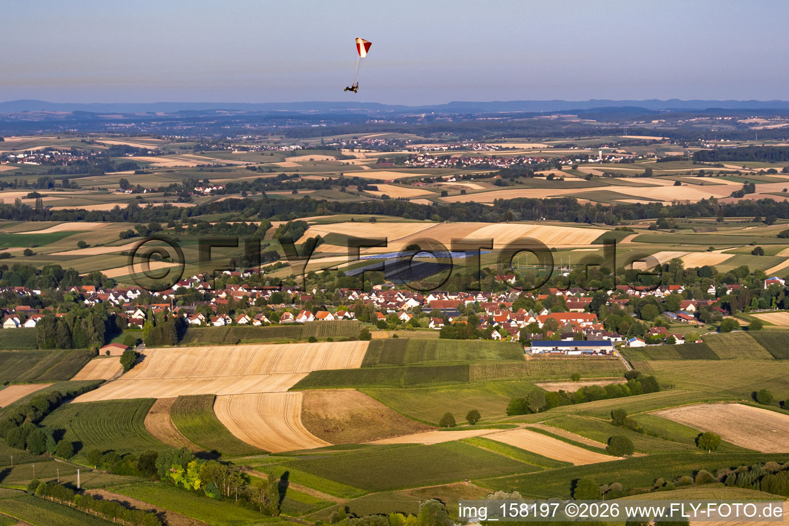 Paraglider over the village viewed from the northeast in Seebach in the state Bas-Rhin, France