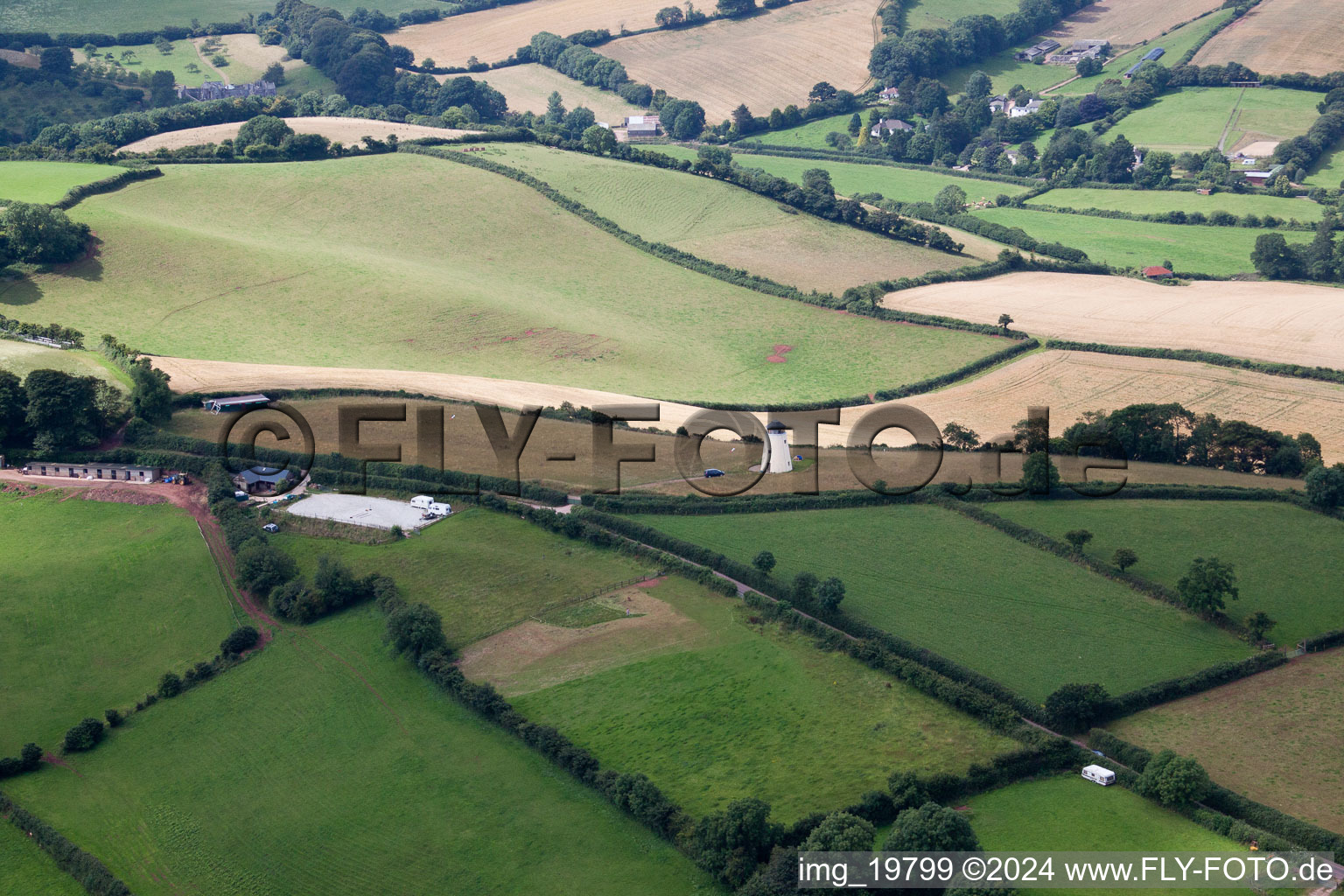 Historic windmill on a farm homestead on the edge of cultivated fields in North Whilborough in England, United Kingdom