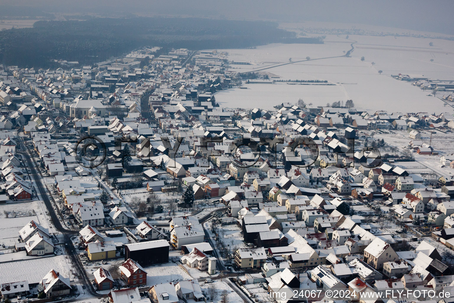 Wintry snowy Village - view on the edge of agricultural fields and farmland in Hatzenbuehl in the state Rhineland-Palatinate, Germany