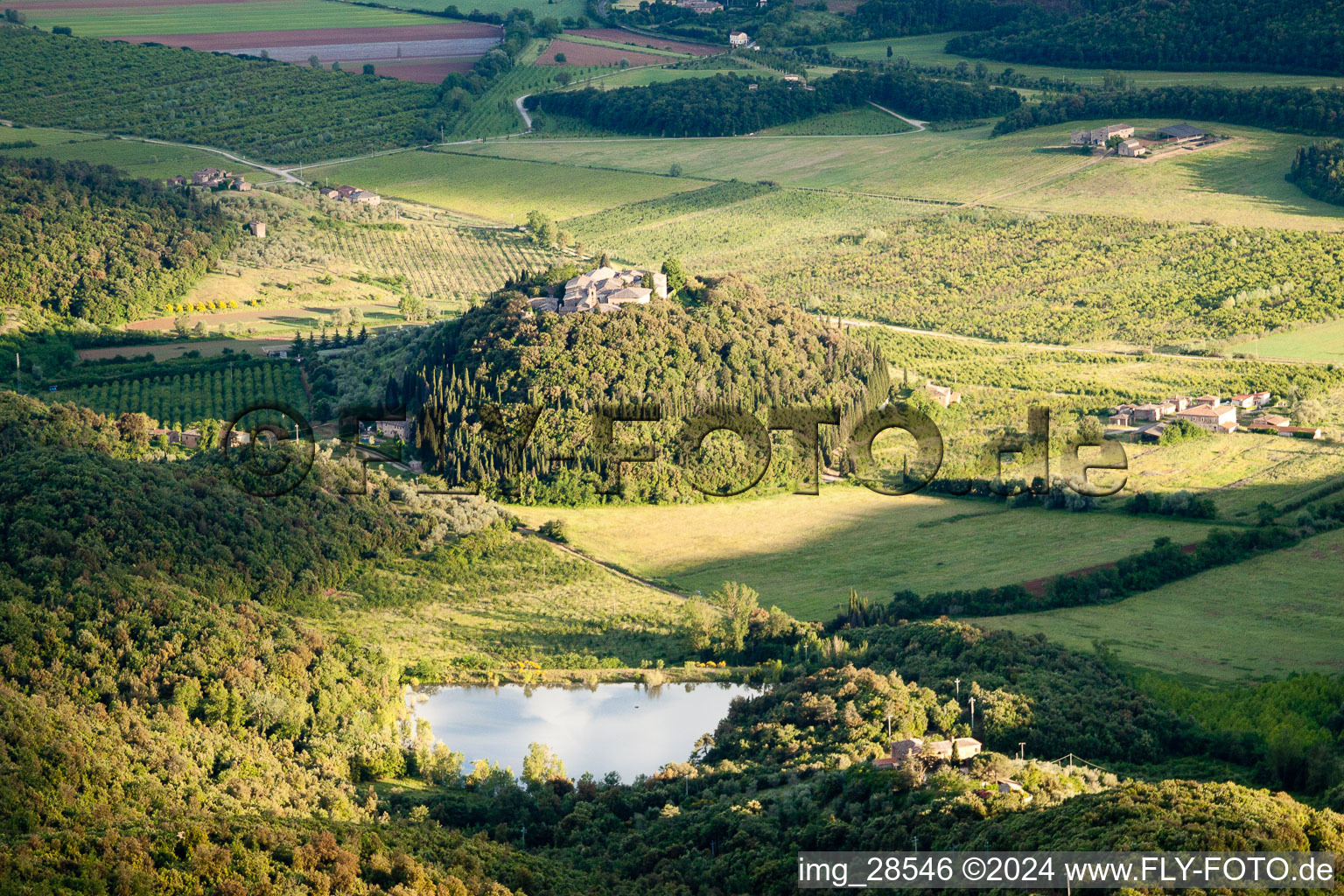 Village - view on a wooded, round hill with lake in the district Poggio Santa Cecilia in Rapolano Terme in the state Siena, Italy