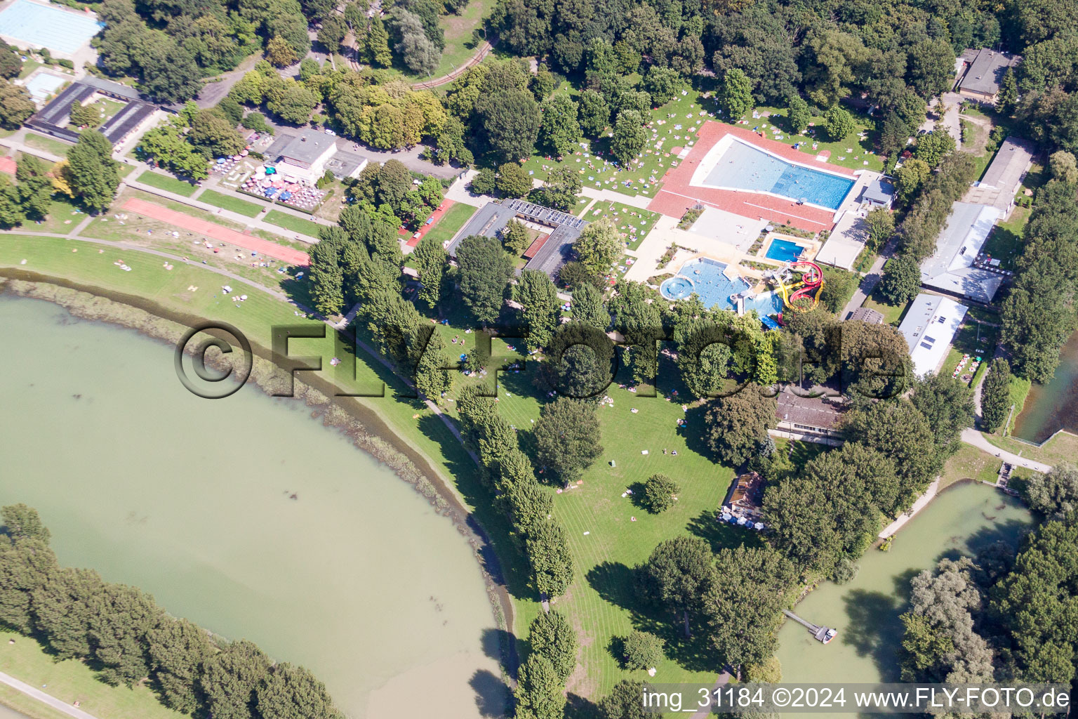 Bathers on the lawn by the pool of the swimming pool Rheinstrandbad Rappenwoert in the district Daxlanden in Karlsruhe in the state Baden-Wurttemberg, Germany