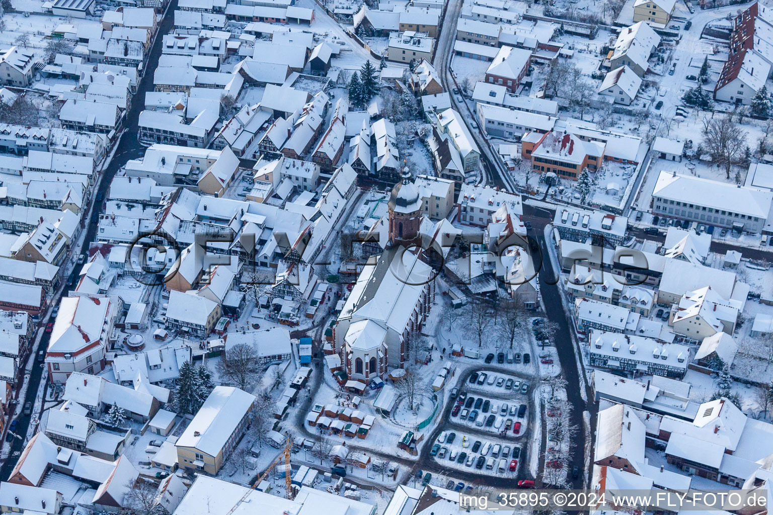 Wintry snowy Christmassy market event grounds and sale huts and booths on market place around tha church Sankt Georgskirche in Kandel in the state Rhineland-Palatinate, Germany