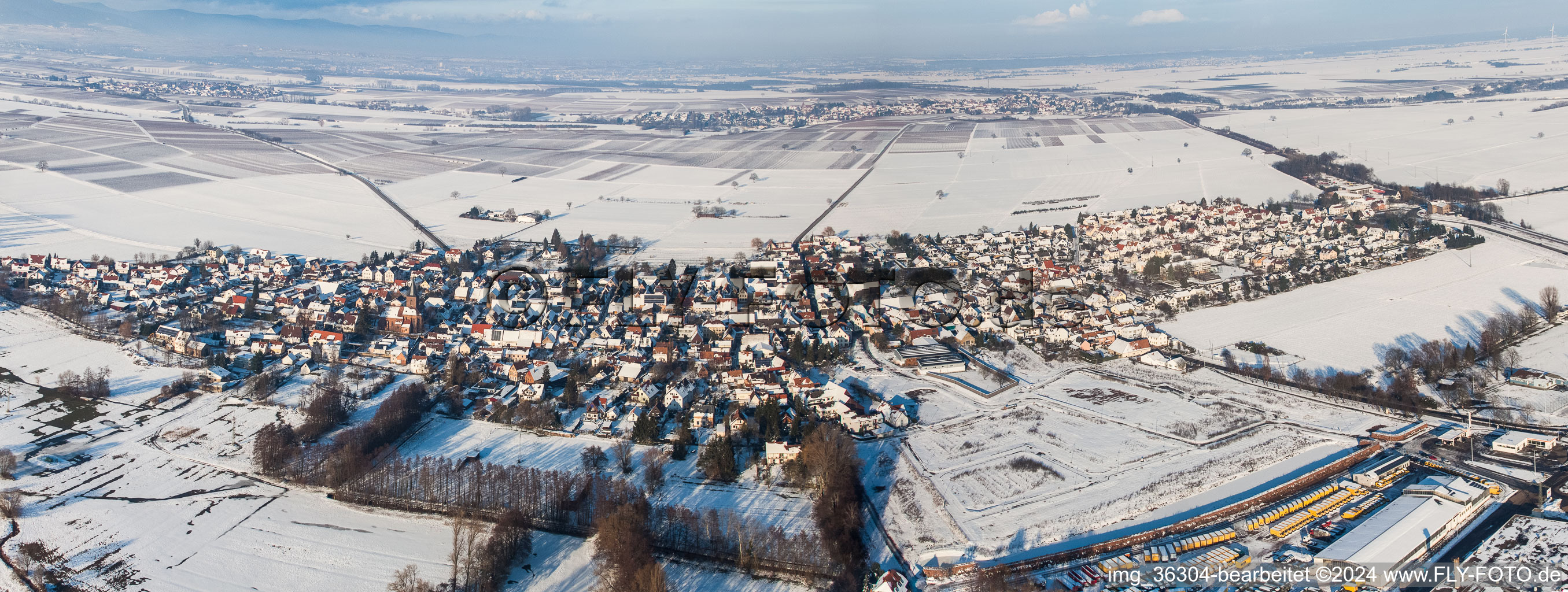 Aerial view of Panorama perspecitve of Wintry snowy Village - view on the edge of agricultural fields and farmland in Rohrbach in the state Rhineland-Palatinate, Germany