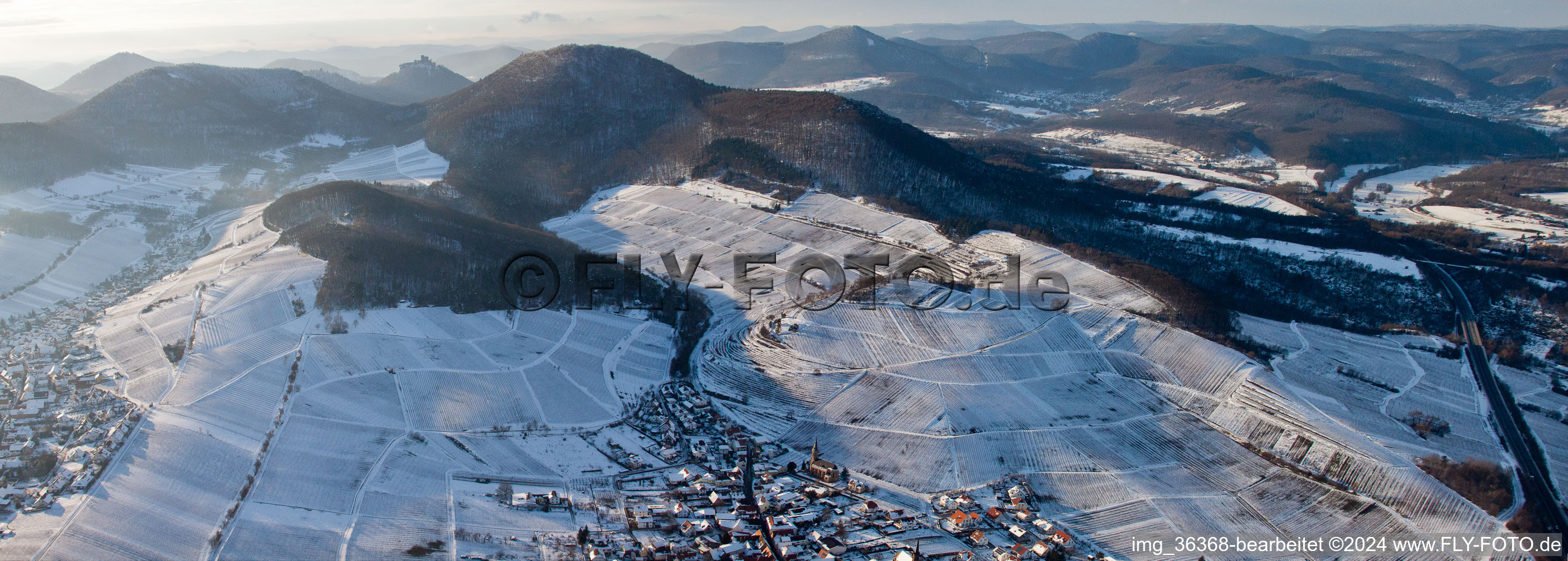 Palatinate Wine villages Birkweiler and Ranschbach and their white and snowy wine yards befor the forest of the hills of the Hohenberg and Trifels in the mountainous landscape in Ranschbach in the state Rhineland-Palatinate