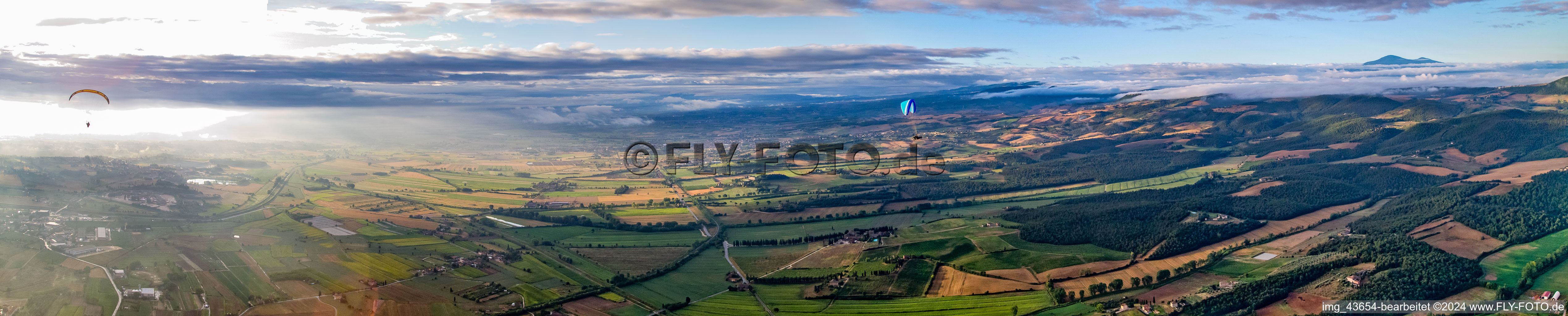 Panorama of sunrise over the landscape with paraglider pilots in Sinalunga in the state Siena, Italy