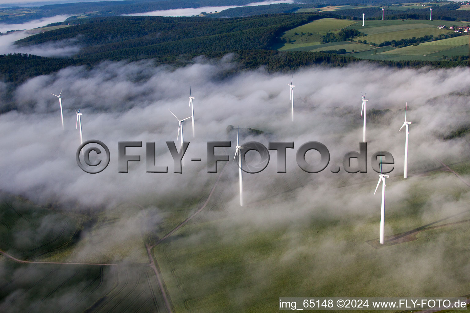 Weather-induced wind energy installations embedded in a fog layer on a field in the district Fuerstenau in Hoexter in the state North Rhine-Westphalia