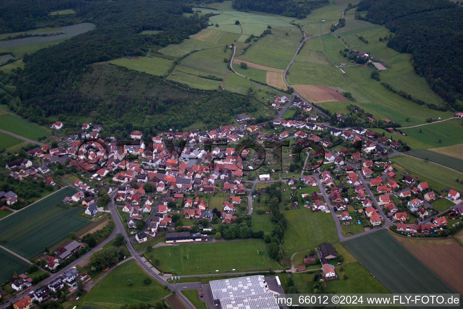 Aerial view of Village - view on the edge of agricultural fields and farmland in Karsbach in the state Bavaria, Germany