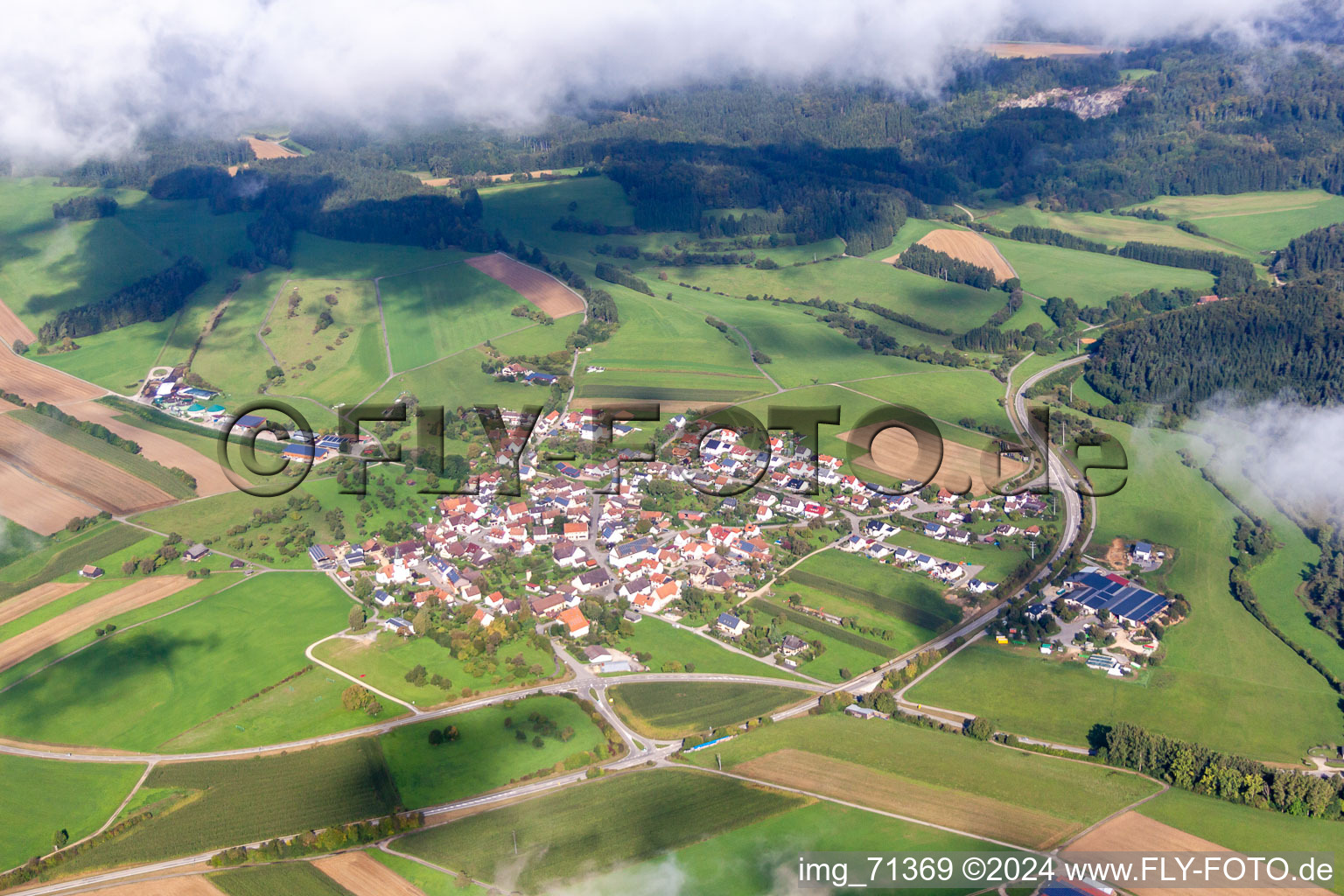 Aerial view of Village - view below low clouds on the edge of agricultural fields and farmland in the district Mauenheim in Immendingen in the state Baden-Wurttemberg, Germany