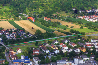 Paraglider over a passenger train on the tracks along the Draisstr in Hemsbach in the state Baden-Wuerttemberg, Germany
