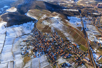 View of the winegrowing village in winter between snow-covered vineyards from the east in Birkweiler in the state Rhineland-Palatinate, Germany