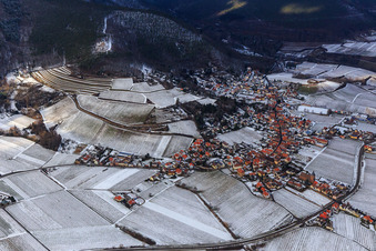 View of a winegrowing village on the edge of the Haardt in winter between snow-covered vineyards from the southeast in Burrweiler in the state Rhineland-Palatinate, Germany