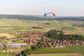 Paradlider over a Village on the edge of agricultural fields and farmland in Ruedenhausen in the state Bavaria, Germany