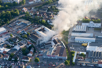 Drone image of Smoke and flames during the fire fighting to fire of a storage all for antiqities in the Werkstrasse in Speyer in the state Rhineland-Palatinate, Germany