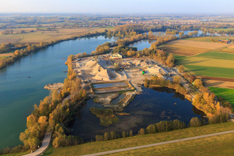 Quarry lake in the Rhine meadows with gravel works of Heidelberg Materials Mineralik in Neupotz in the state Rhineland-Palatinate, Germany