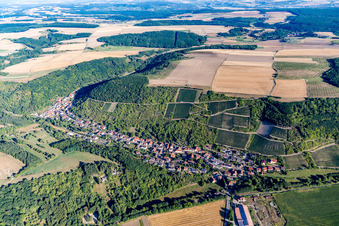 Agricultural land and field borders surround the settlement area of the village in Raumbach in the state Rhineland-Palatinate, Germany
