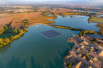 Floating solar power plant and panels of photovoltaic systems on the surface of the water on a quarry pond for gravel extraction in Leimersheim in the state Rhineland-Palatinate, Germany from above