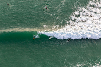 Wave surfers in front of the Plage de Tronoën in Saint-Jean-Trolimon in the state Finistere, France from the plane