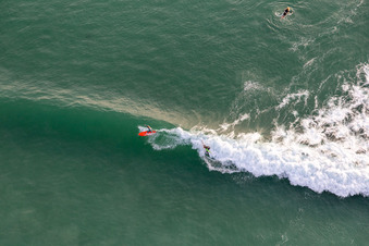 Bird's eye view of Wave surfers in front of the Plage de Tronoën in Saint-Jean-Trolimon in the state Finistere, France