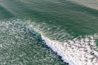 Aerial view of Wave surfers in front of the Plage de Tronoën in Saint-Jean-Trolimon in the state Finistere, France