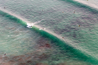 Aerial view of Wave surfers in front of Plage la Torche-Tronoën in Saint-Jean-Trolimon in the state Finistere, France