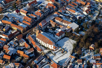 Main street with parish church of St. Michael in winter with snow in Rheinzabern in the state Rhineland-Palatinate, Germany out of the air
