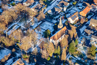 Wolfgangskirche and cemetery in winter with snow in Freckenfeld in the state Rhineland-Palatinate, Germany