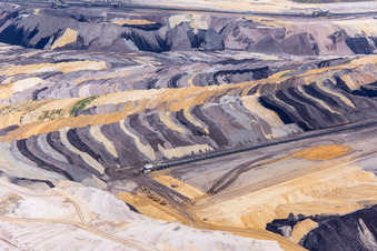 Interestingly colored layers of overburden and coal in the Garzweiler opencast lignite mine in the district Borschemich in Erkelenz in the state North Rhine-Westphalia, Germany seen from above