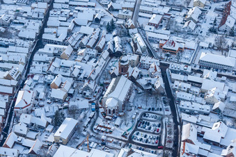 Wintry snowy Christmassy market event grounds and sale huts and booths on market place around tha church Sankt Georgskirche in Kandel in the state Rhineland-Palatinate, Germany