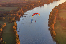 NATO ramp Gernsheim with paraglider over cargo ship on the Rhine at sunset in Gernsheim in the state Hesse, Germany