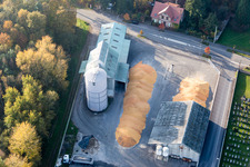 Corn mountains in the courtyard of the high silo and grain storage with adjacent warehouses of the Comptoir agricole - NIEDERROEDERN in Niederrœdern in the state Bas-Rhin, France