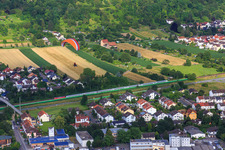 Paraglider over a passenger train on the tracks along the Draisstr in Hemsbach in the state Baden-Wuerttemberg, Germany