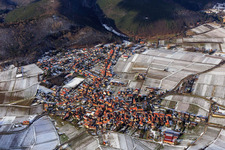 View of a winegrowing village on the edge of the Haardt in winter between snow-covered vineyards from the south in Frankweiler in the state Rhineland-Palatinate, Germany