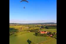 Paraglider over the estate Mariaburghausen with the Church of St. John the Baptist Mariaburghausen in the district Mariaburghausen in Haßfurt in the state Bavaria, Germany