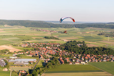 Paradlider over a Village on the edge of agricultural fields and farmland in Ruedenhausen in the state Bavaria, Germany