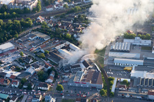 Drone recording of Smoke and flames during the fire fighting to fire of a storage all for antiqities in the Werkstrasse in Speyer in the state Rhineland-Palatinate, Germany