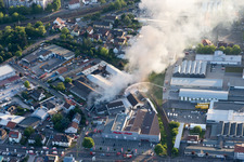 Drone image of Smoke and flames during the fire fighting to fire of a storage all for antiqities in the Werkstrasse in Speyer in the state Rhineland-Palatinate, Germany
