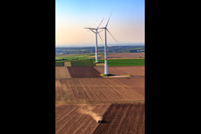 Tractor plowing in front of two wind turbines at the wind farm north of Bechtheim in the district Heßloch in Dittelsheim-Heßloch in the state Rhineland-Palatinate, Germany