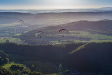 Forest and mountain scenery with 3 Paragleitern in Weserbergland in Holenberg in the state Lower Saxony, Germany
