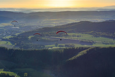 Aerial view of Three paragliders in the morning in Holenberg in the state Lower Saxony, Germany