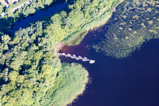 Riparian areas on the swamp coloured (Smaland) lake Asnen with water lillys, boat bridge, and swimming beach in Torne in Kronobergs laen, Sweden