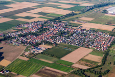 Agricultural land and field borders surround the settlement area of the village in Ottersheim bei Landau in the state Rhineland-Palatinate, Germany from the drone perspective