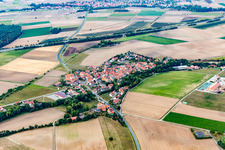 Aerial view of Agricultural land and field borders surround the settlement area of the village in Feuerbach in the state Bavaria, Germany