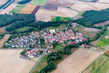 Aerial view of Agricultural land and field borders surround the settlement area of the village in Atzhausen in the state Bavaria, Germany
