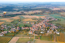 Agricultural land and field borders surround the settlement area of the village with hot air ballon in Kindwiller in Grand Est, France