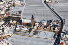 Wintry snowy church building of Catholic parish church of the Visitation of Mary, the wine house Vinothek Messmer, Ritterhof zur Rose in Burrweiler in the state Rhineland-Palatinate, Germany