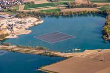 Aerial view of Floating solar power plant and panels of photovoltaic systems on the surface of the water on a quarry pond for gravel extraction in Leimersheim in the state Rhineland-Palatinate, Germany