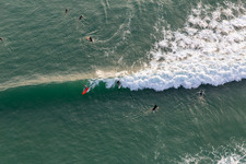 Wave surfers in front of the Plage de Tronoën in Saint-Jean-Trolimon in the state Finistere, France seen from above