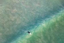 Drone image of Wave surfers in front of the Plage de Tronoën in Saint-Jean-Trolimon in the state Finistere, France