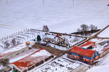 Village market Schoßberghof In winter with snow in Minfeld in the state Rhineland-Palatinate, Germany from above