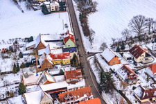 Main street in winter in the snow in Hergersweiler in the state Rhineland-Palatinate, Germany viewn from the air